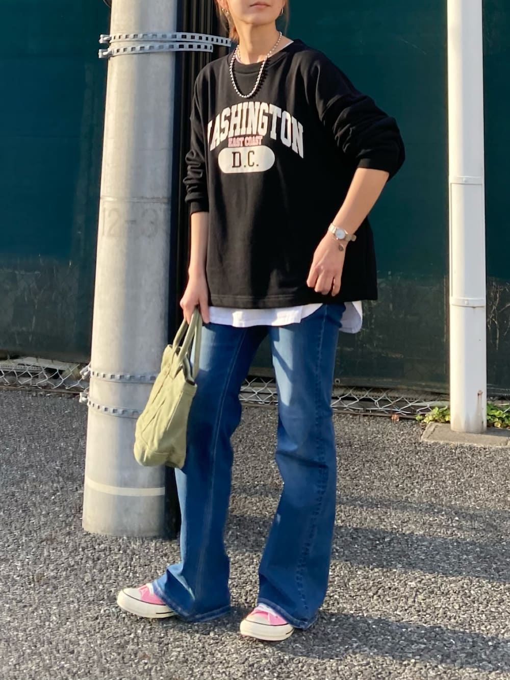 ブラック系のスウェット、ブルー系のデニムパンツ、グリーン系のトートバッグを着用したレディースの春コーディネートの2枚目の写真