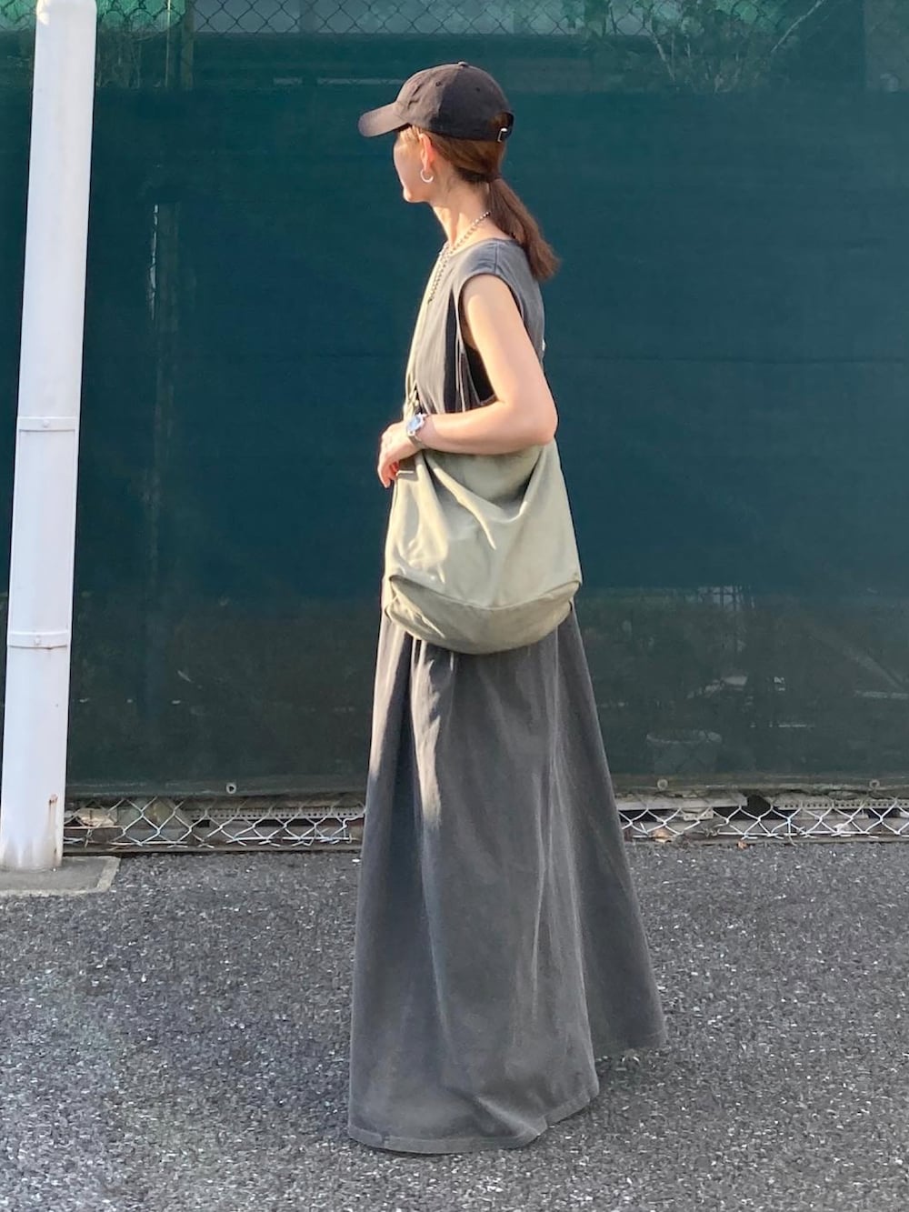 グリーン系のショルダーバッグ、グレー系のワンピース、シルバー系のスニーカーを着用したレディースの夏コーディネートの2枚目の写真