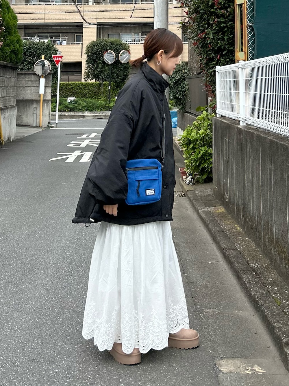 ブラック系のブルゾン、ベージュ系のブーツ、ホワイト系のスカートを着用したレディースの秋コーディネートの2枚目の写真