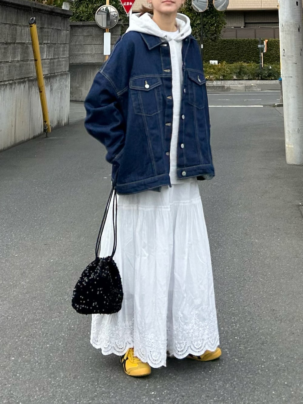 ブルー系のデニムジャケット、グレー系のパーカー、ホワイト系のスカートを着用したレディースの春コーディネートの3枚目の写真