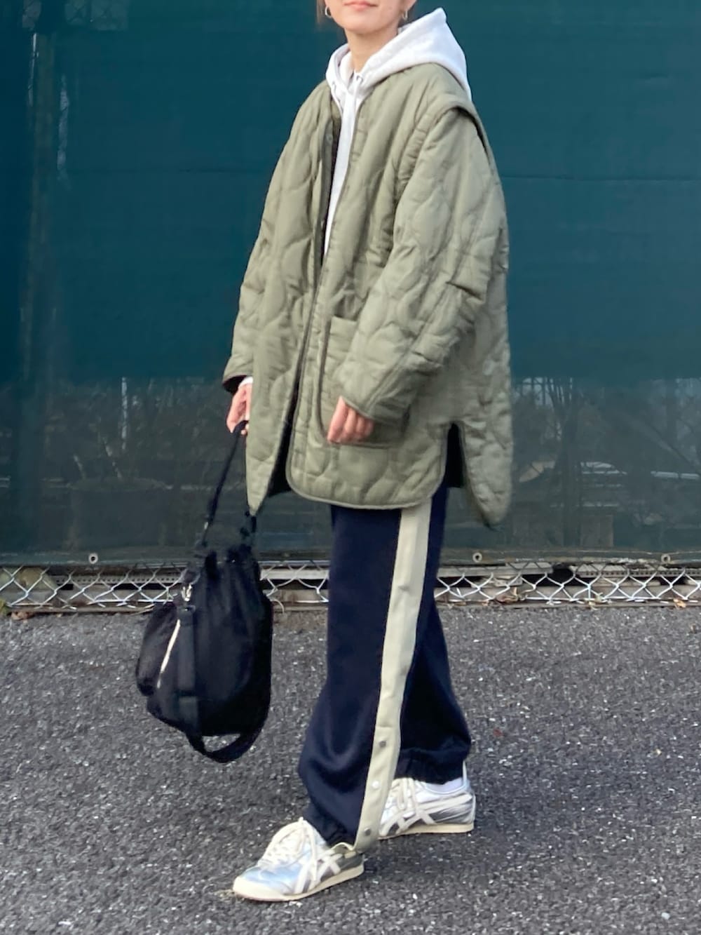 グリーン系のブルゾン、グレー系のパーカー、ブルー系のスウェットパンツを着用したレディースの冬コーディネートの2枚目の写真