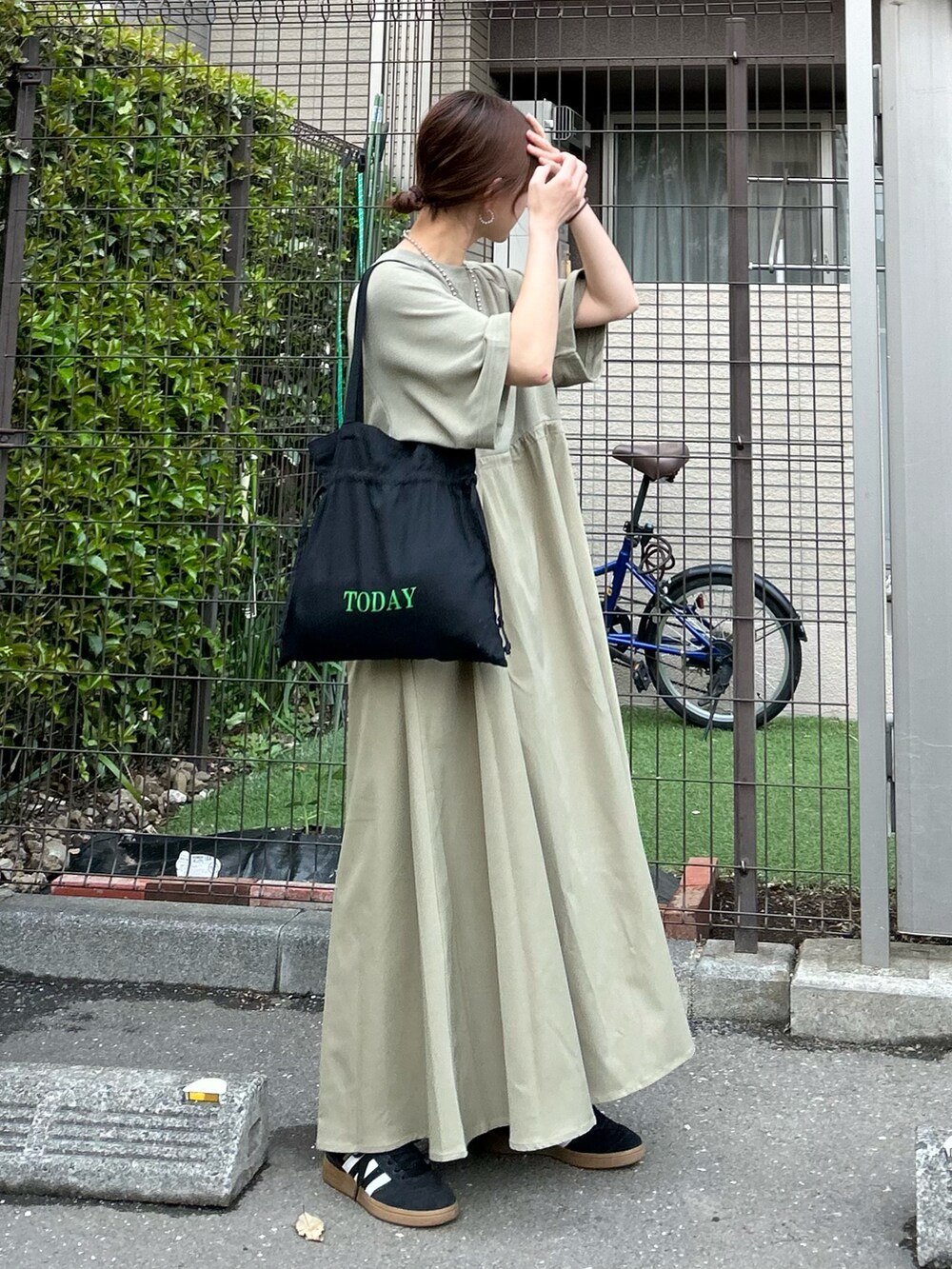 グリーン系のワンピース、ブラック系のトートバッグ、ブルー系のデニムジャケットを着用したレディースの春コーディネートの2枚目の写真