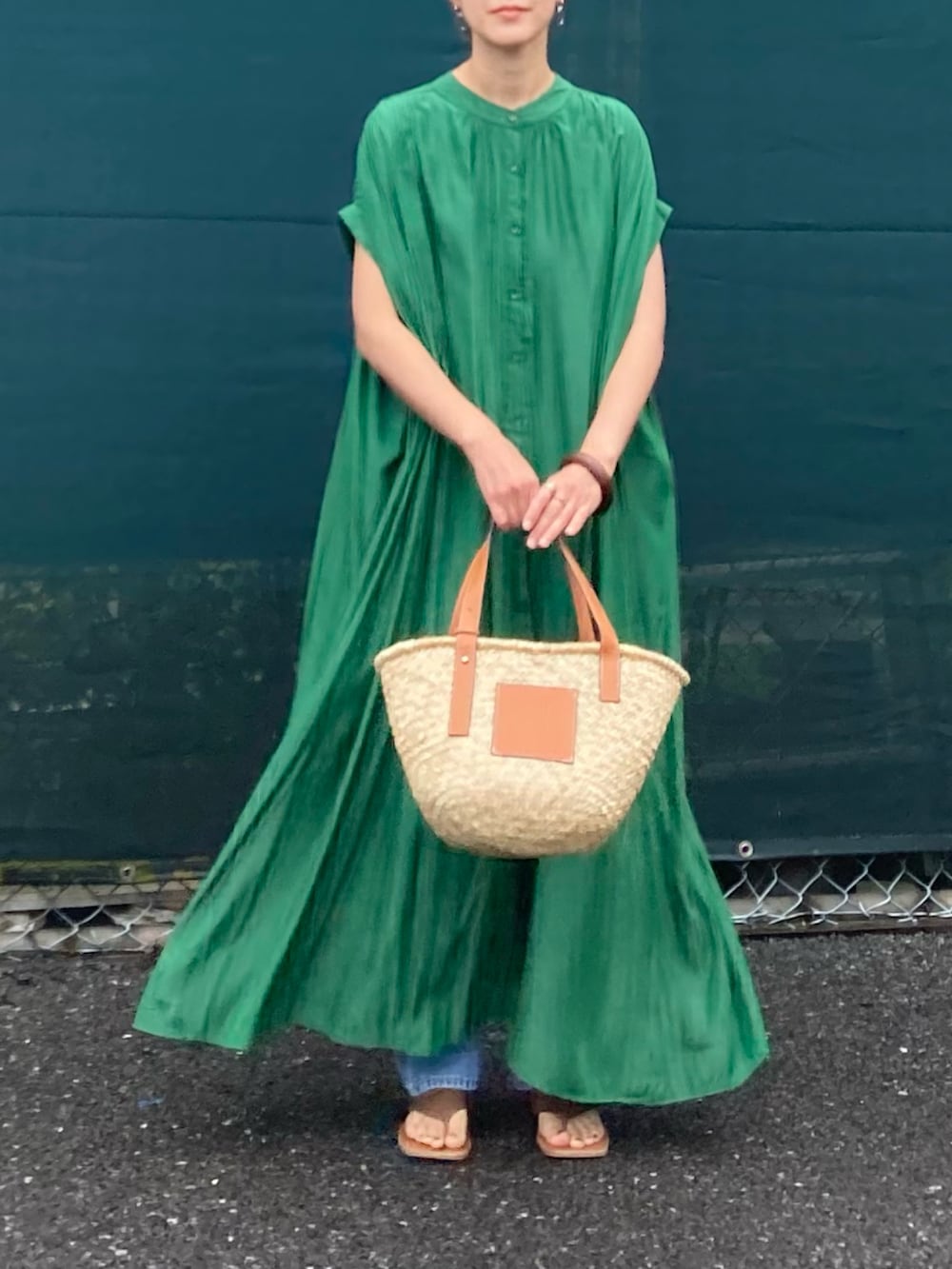 グリーン系のシャツワンピース、ブラウン系のかごバッグ、ブルー系のデニムパンツを着用したレディースの夏コーディネートの3枚目の写真