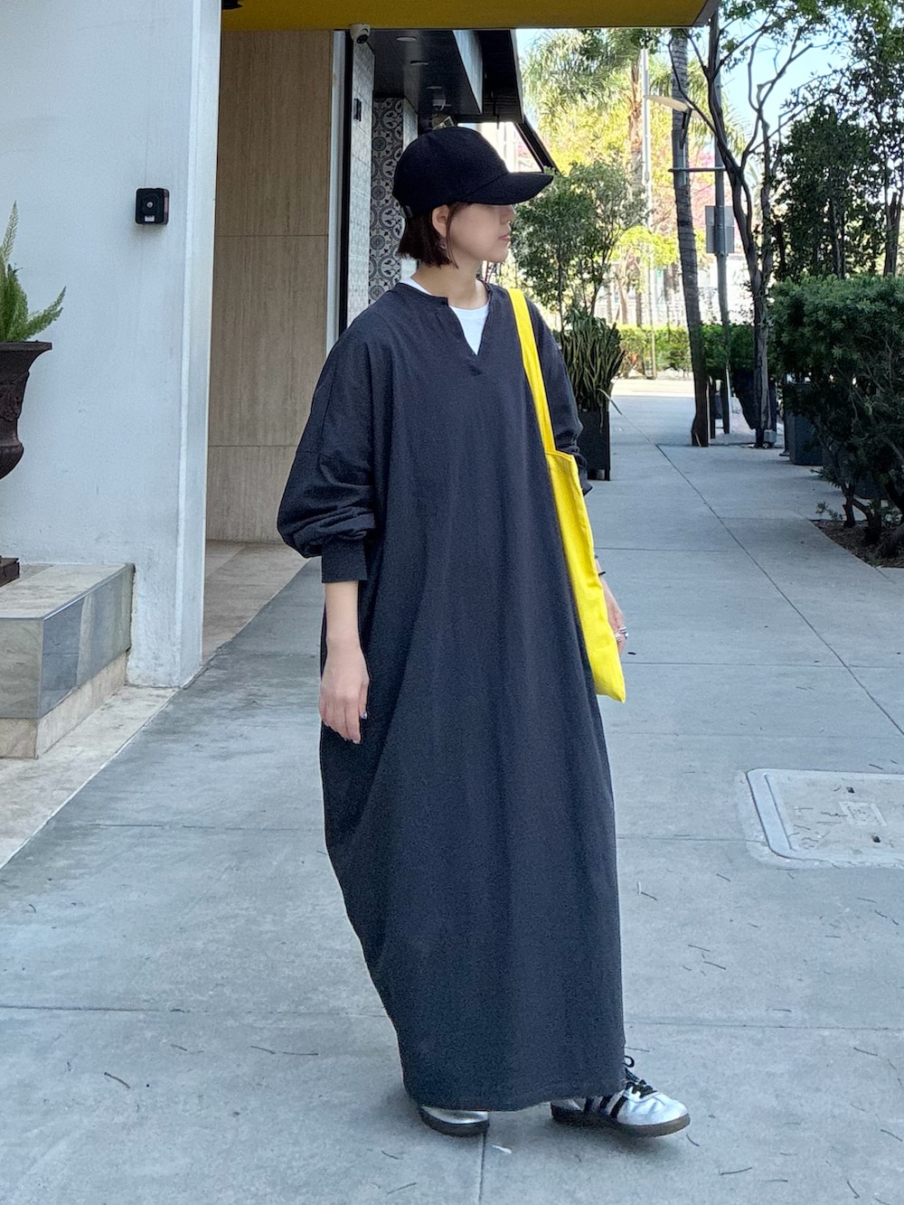 グレー系のワンピース、イエロー系のトートバッグ、シルバー系のスニーカーを着用したレディースの春コーディネートの3枚目の写真