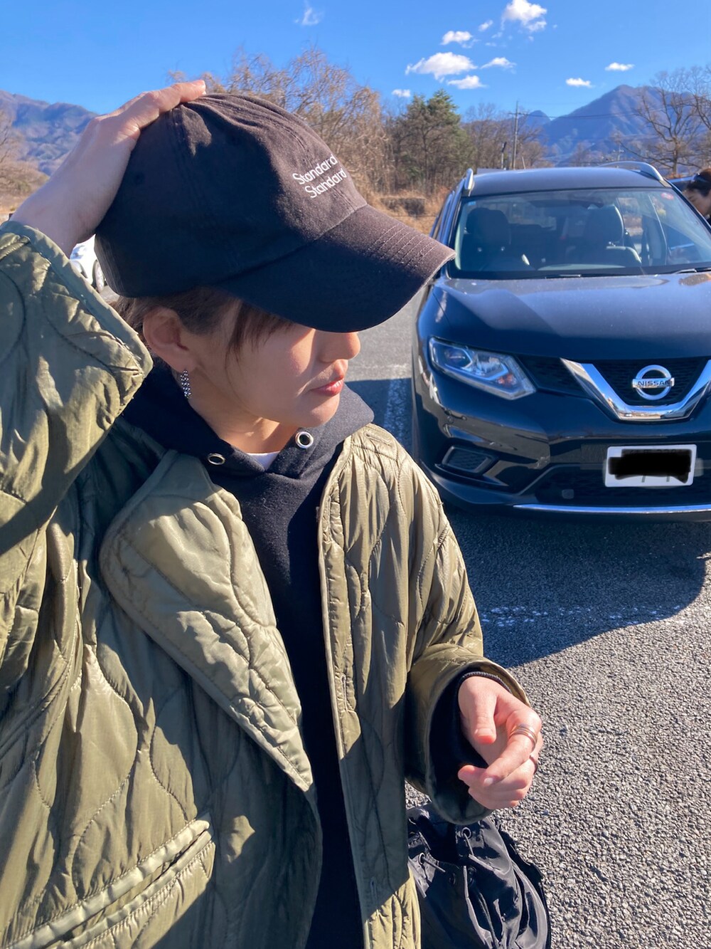 ブラック系のワンピース、ブラック系のショルダーバッグ、グリーン系のノーカラージャケットを着用したレディースの冬コーディネートの4枚目の写真