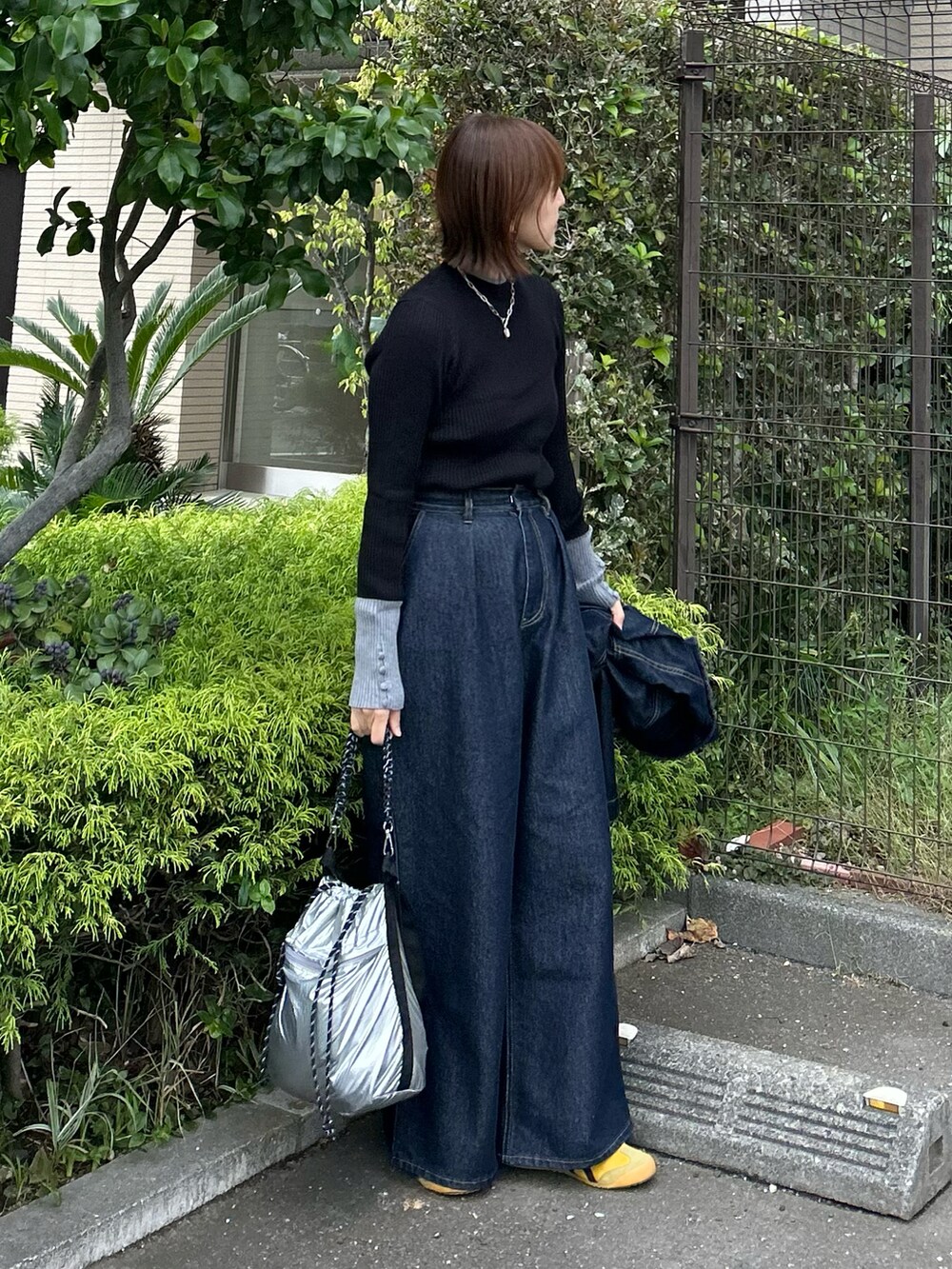 ホワイト系のダウンベスト、ブラック系のニット/セーター、ブルー系のデニムパンツを着用したレディースの秋コーディネートの3枚目の写真