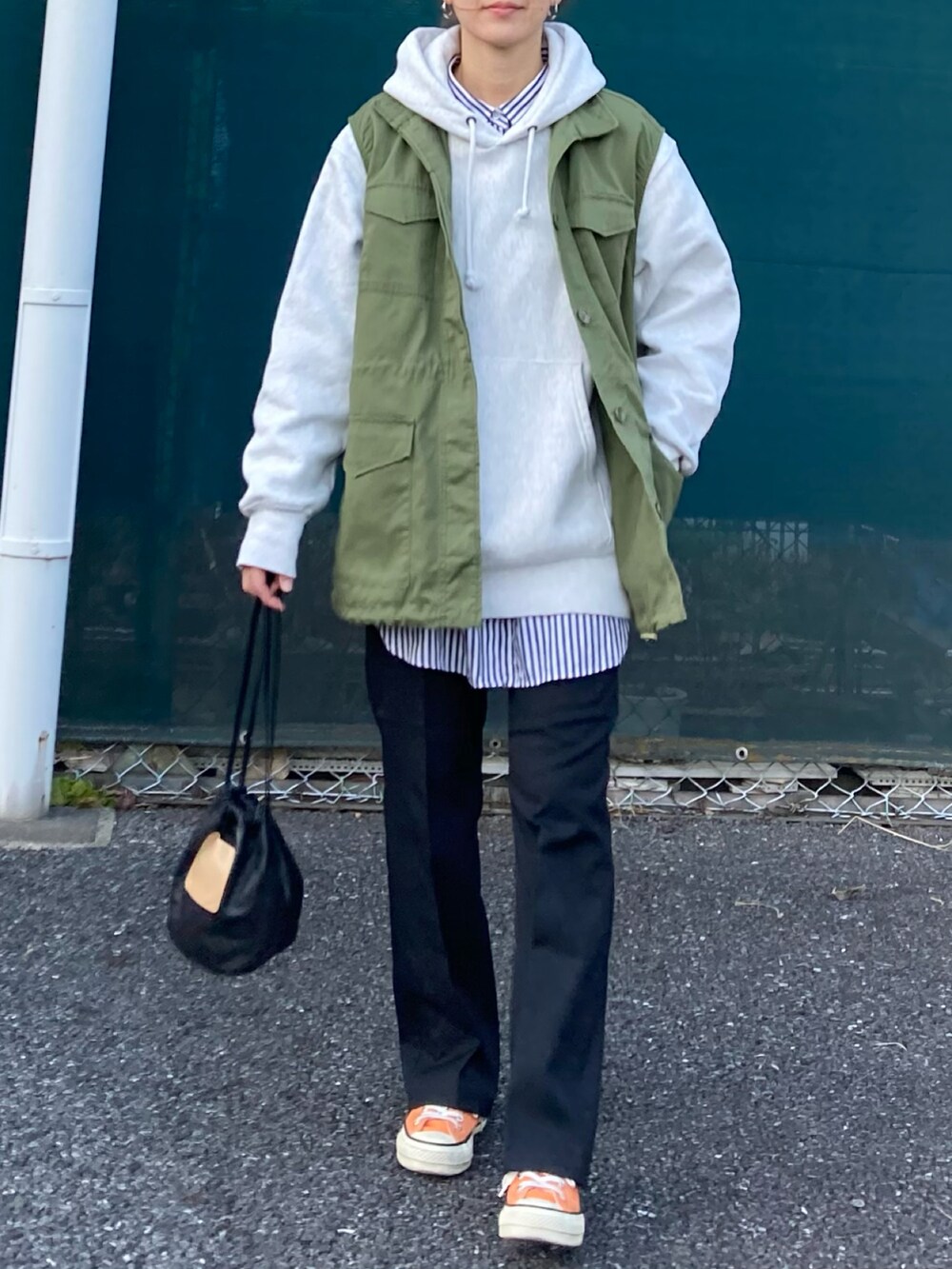 グリーン系のベスト、グレー系のパーカー、ブラック系のスラックスを着用したレディースの冬コーディネートの2枚目の写真
