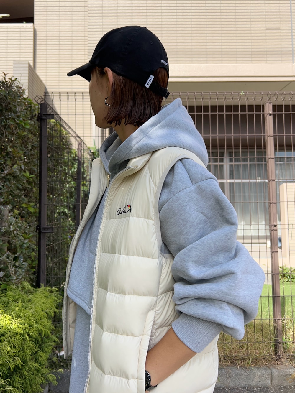 グレー系のワンピース、ブラック系のトートバッグ、ホワイト系のダウンベストを着用したレディースの秋コーディネートの5枚目の写真