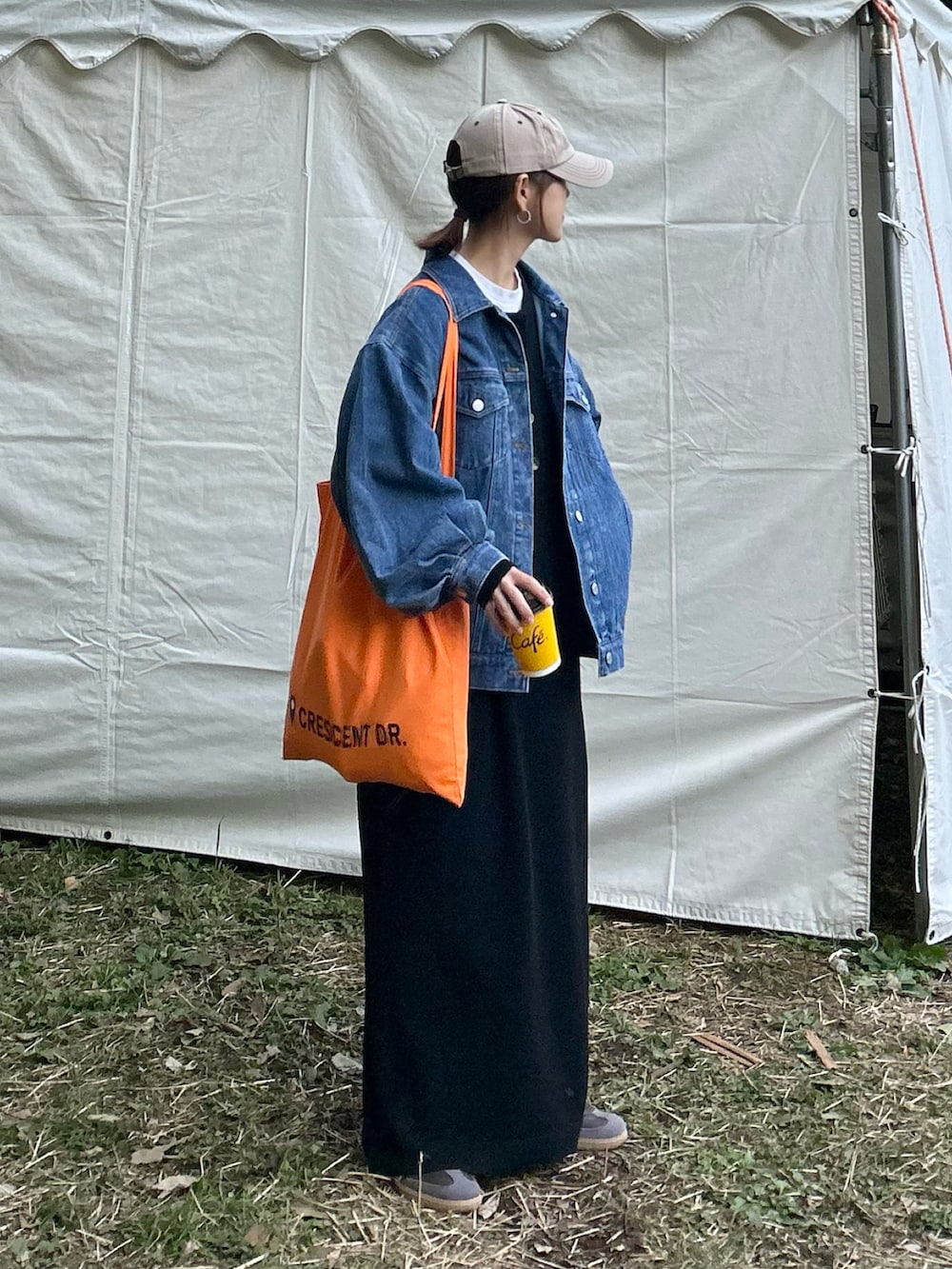 ブラック系のワンピース、ブルー系のデニムジャケット、オレンジ系のトートバッグを着用したレディースの冬コーディネートの3枚目の写真