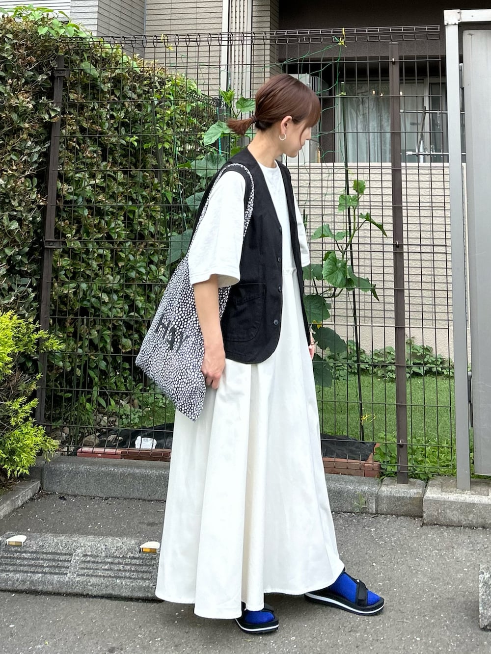 ベージュ系のワンピース、ブラック系のベスト、ブラック系のサンダルを着用したレディースの夏コーディネートの3枚目の写真