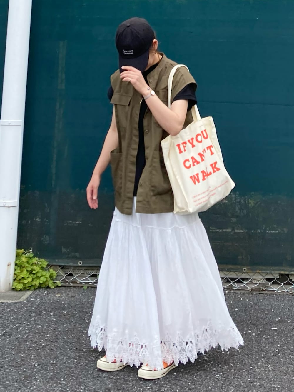 グリーン系のベスト、ブラック系のTシャツ/カットソー、ベージュ系のトートバッグを着用したレディースの夏コーディネートの5枚目の写真