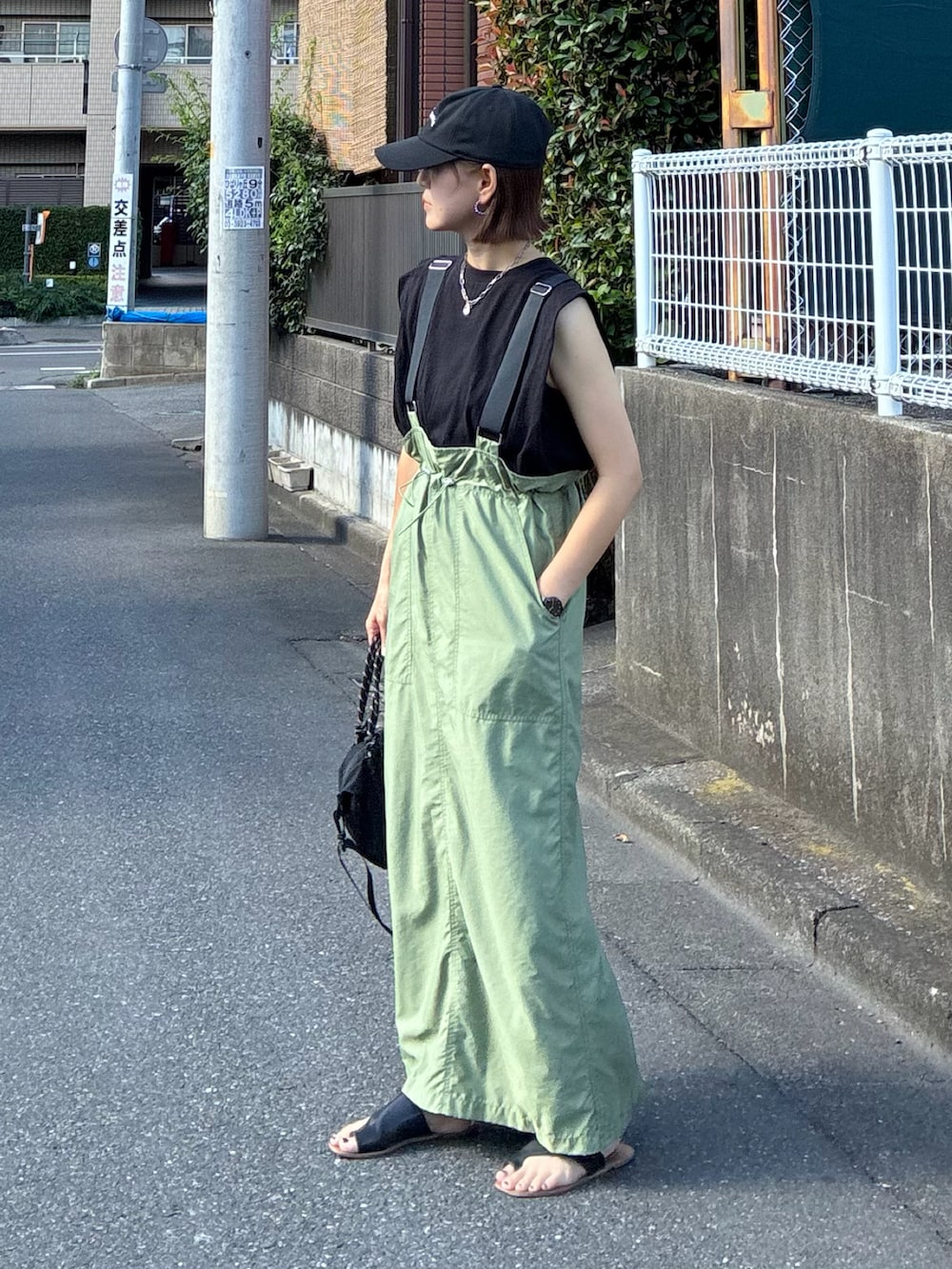 ブラック系のTシャツ/カットソー、グリーン系のジャンパースカート、ブラック系のトートバッグを着用したレディースの夏コーディネートの5枚目の写真