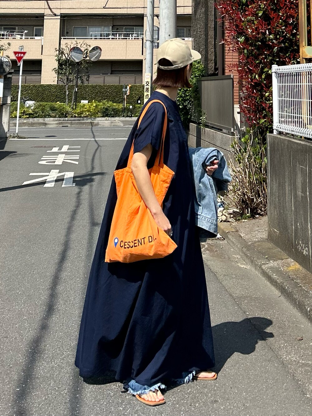 ブルー系のワンピース、オレンジ系のトートバッグ、ベージュ系のキャップを着用したレディースの夏コーディネートの3枚目の写真