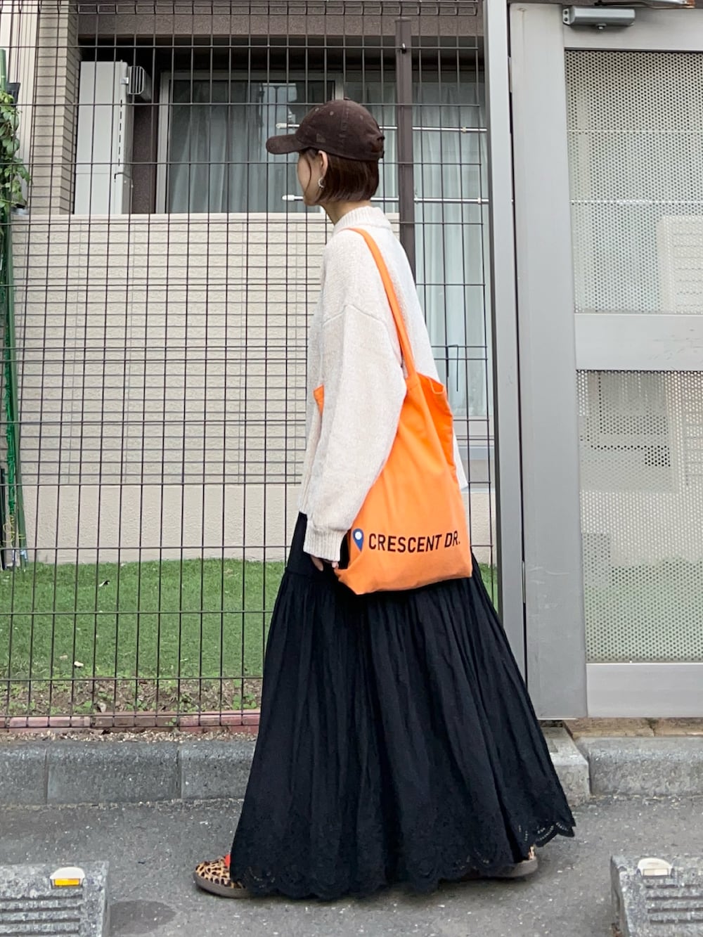 ベージュ系のニット/セーター、ブラック系のスカート、オレンジ系のトートバッグを着用したレディースの冬コーディネートの2枚目の写真