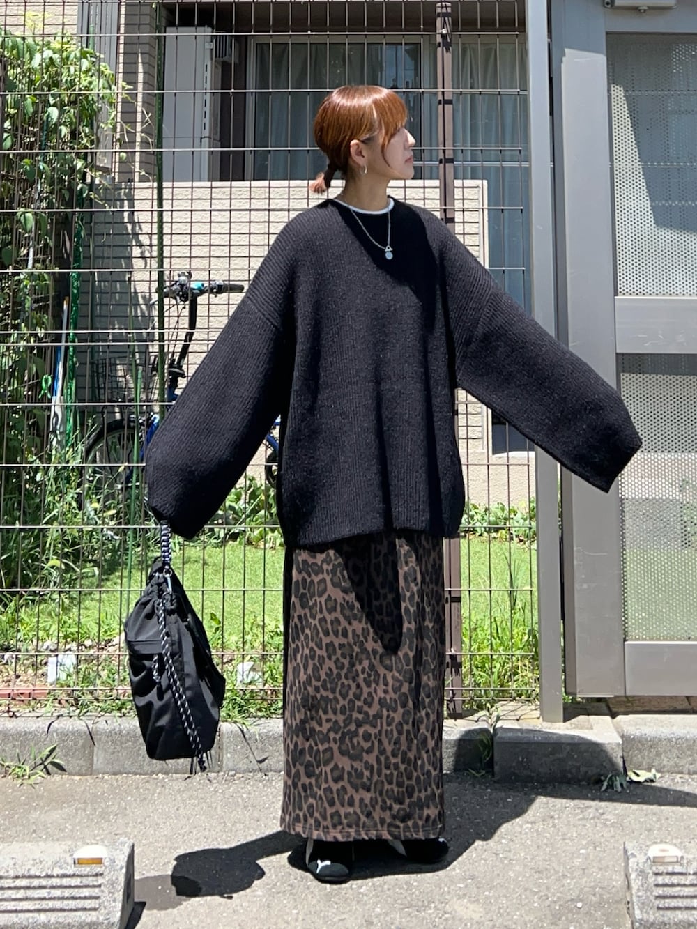 ブラック系のニット/セーター、ブラック系のトートバッグ、ブラウン系のスカートを着用したレディースの夏コーディネートの3枚目の写真