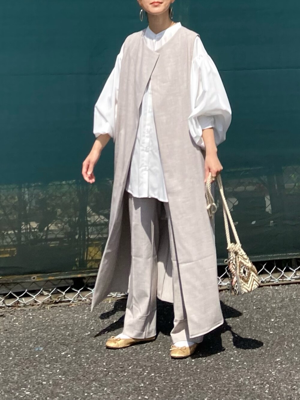 ホワイト系のシャツ/ブラウス、ベージュ系のベスト、ベージュ系のスラックスを着用したレディースの春コーディネートの4枚目の写真