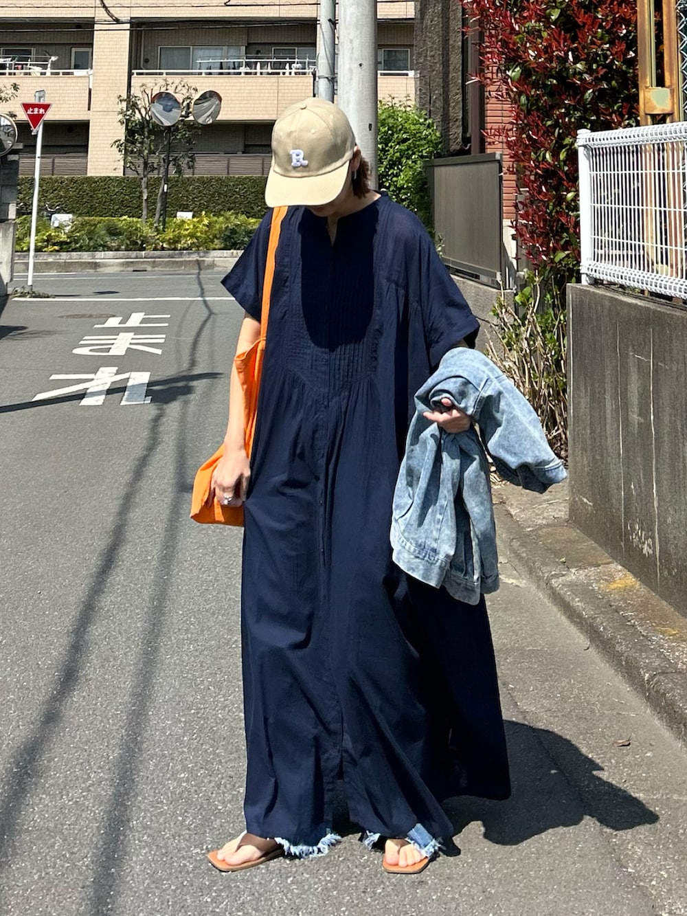 ブルー系のワンピース、オレンジ系のトートバッグ、ベージュ系のキャップを着用したレディースの夏コーディネートの2枚目の写真