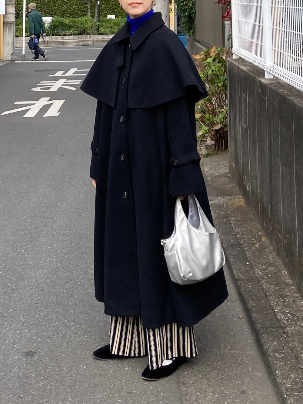 ブラック系のステンカラーコート、ブルー系のニット/セーター、ブラック系のその他パンツを着用したレディースの秋コーディネートの3枚目の写真