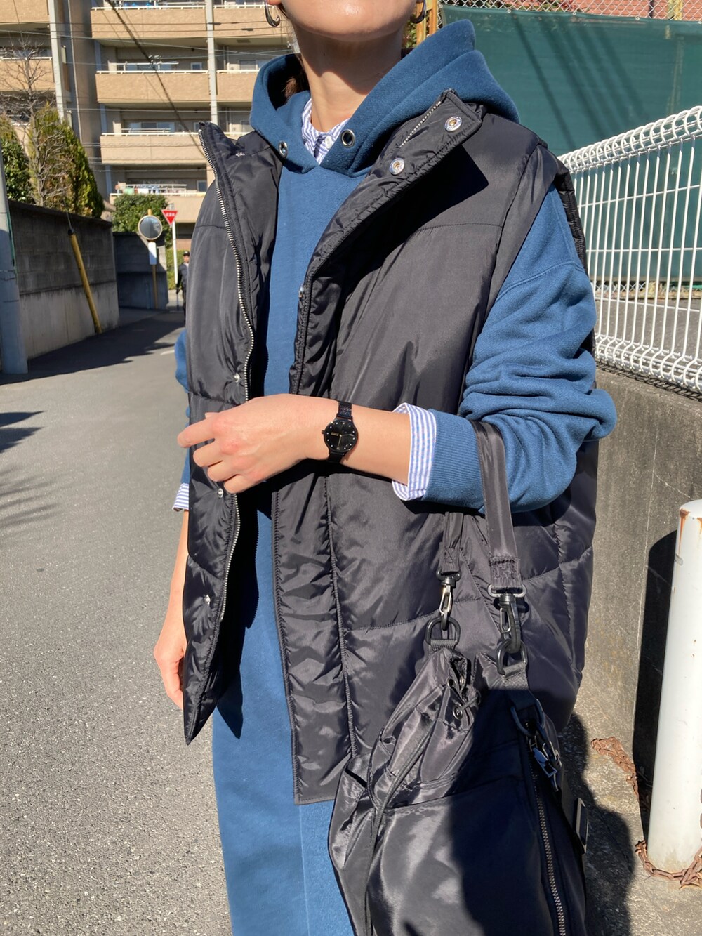 ブラック系のダウンベスト、ブルー系のワンピース、ブラック系のショルダーバッグを着用したレディースの冬コーディネートの4枚目の写真