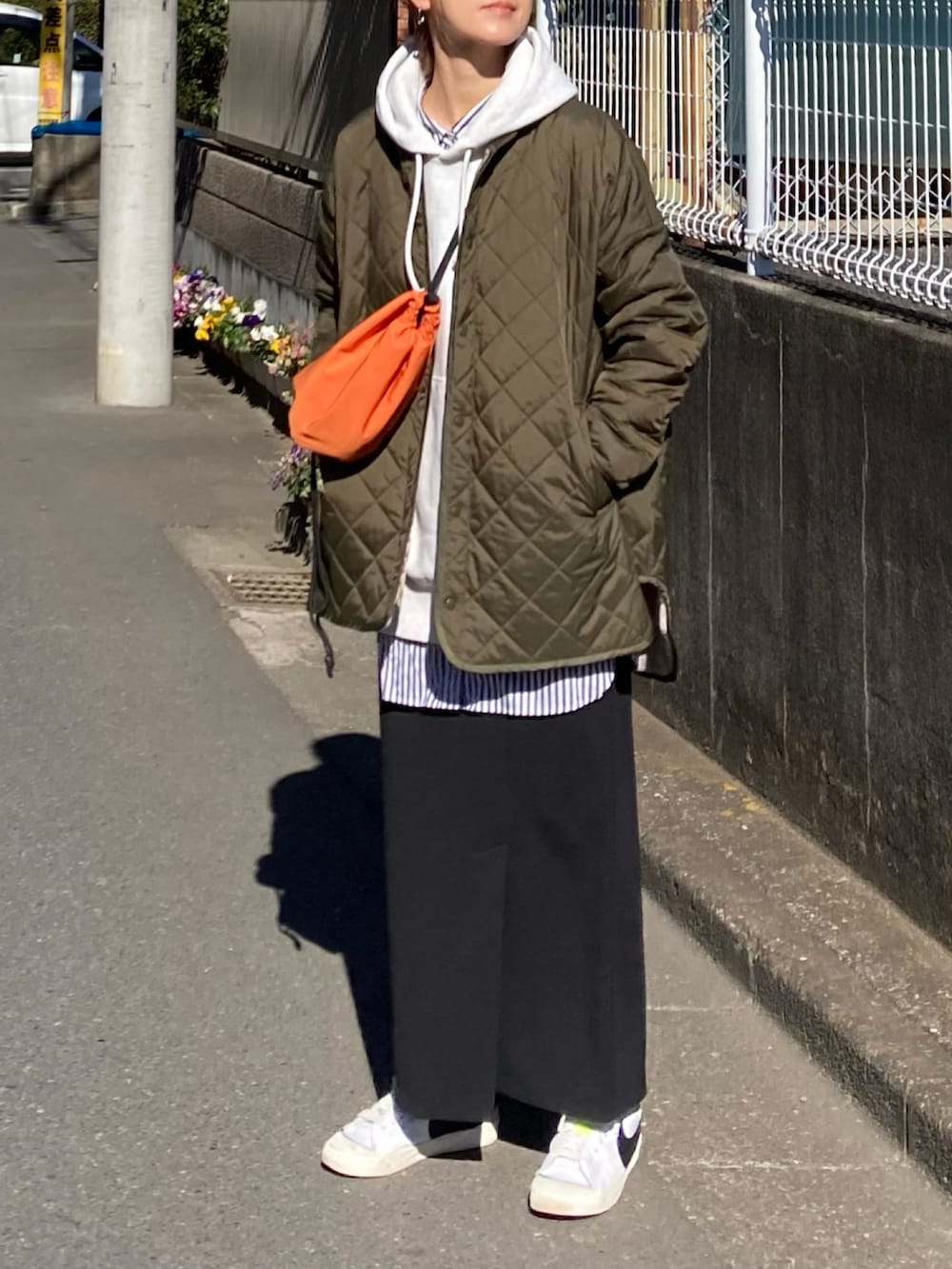 グリーン系のブルゾン、グレー系のパーカー、ブラック系のスカートを着用したレディースの冬コーディネートの2枚目の写真