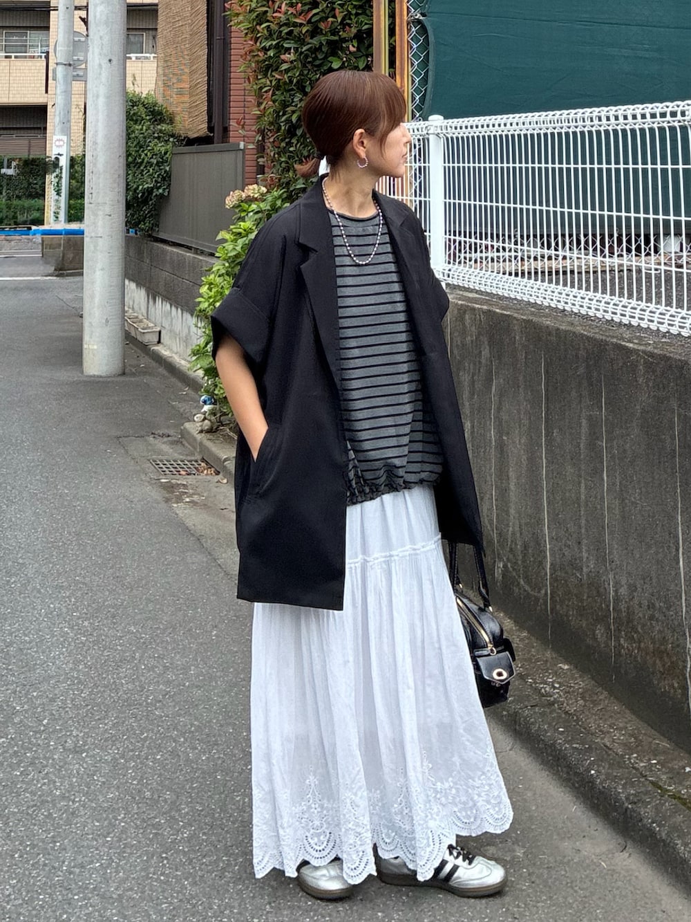 ブラック系のテーラードジャケット、グレー系のTシャツ/カットソー、ホワイト系のスカートを着用したレディースの秋コーディネートの2枚目の写真