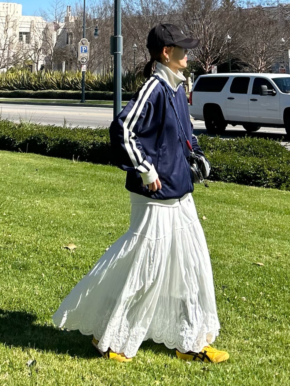 ブルー系のジャージ、ホワイト系のスカート、グレー系のショルダーバッグを着用したレディースの冬コーディネートの2枚目の写真