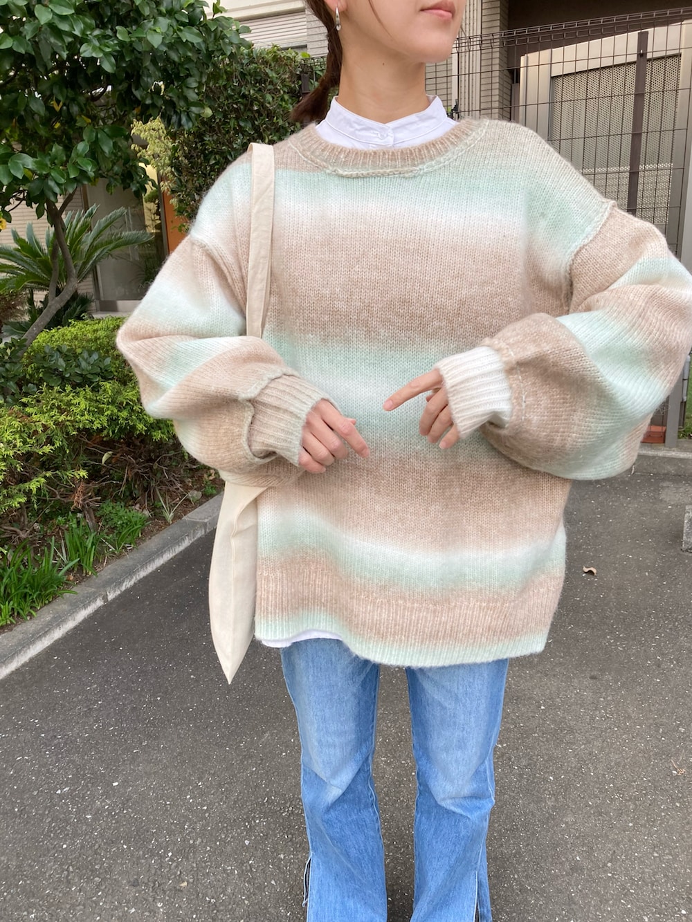 グリーン系のカーディガン/ボレロ、ホワイト系のシャツ/ブラウス、ブルー系のデニムパンツを着用したレディースの秋コーディネートの2枚目の写真