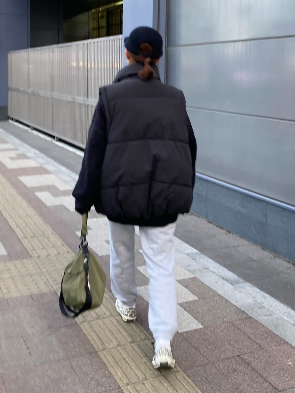 ブラック系のダウンベスト、グリーン系のショルダーバッグ、ブラック系のニット/セーターを着用したレディースの冬コーディネートの3枚目の写真