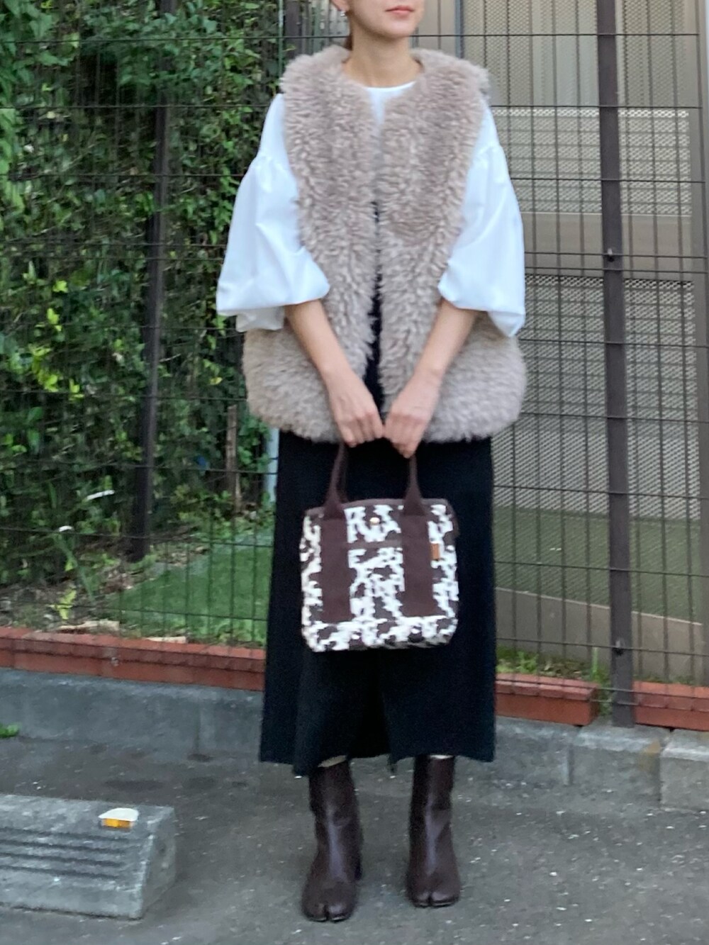 ベージュ系のベスト、ホワイト系のシャツ/ブラウス、ブラック系のジャンパースカートを着用したレディースの秋コーディネートの3枚目の写真