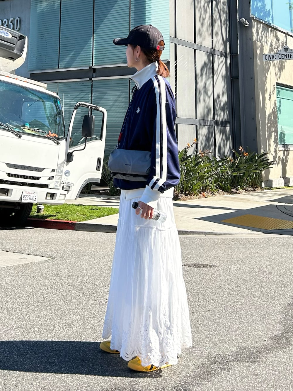 ブルー系のジャージ、ホワイト系のスカート、グレー系のショルダーバッグを着用したレディースの冬コーディネートの4枚目の写真