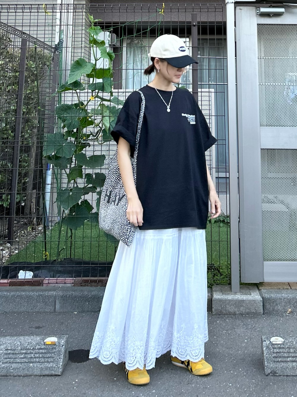 ブラック系のTシャツ/カットソー、ホワイト系のスカート、イエロー系のスニーカーを着用したレディースの夏コーディネートの2枚目の写真