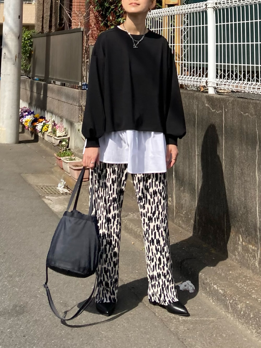 ブラック系のアンサンブル、ホワイト系のその他パンツ、ブラック系のバッグを着用したレディースの春コーディネートの2枚目の写真