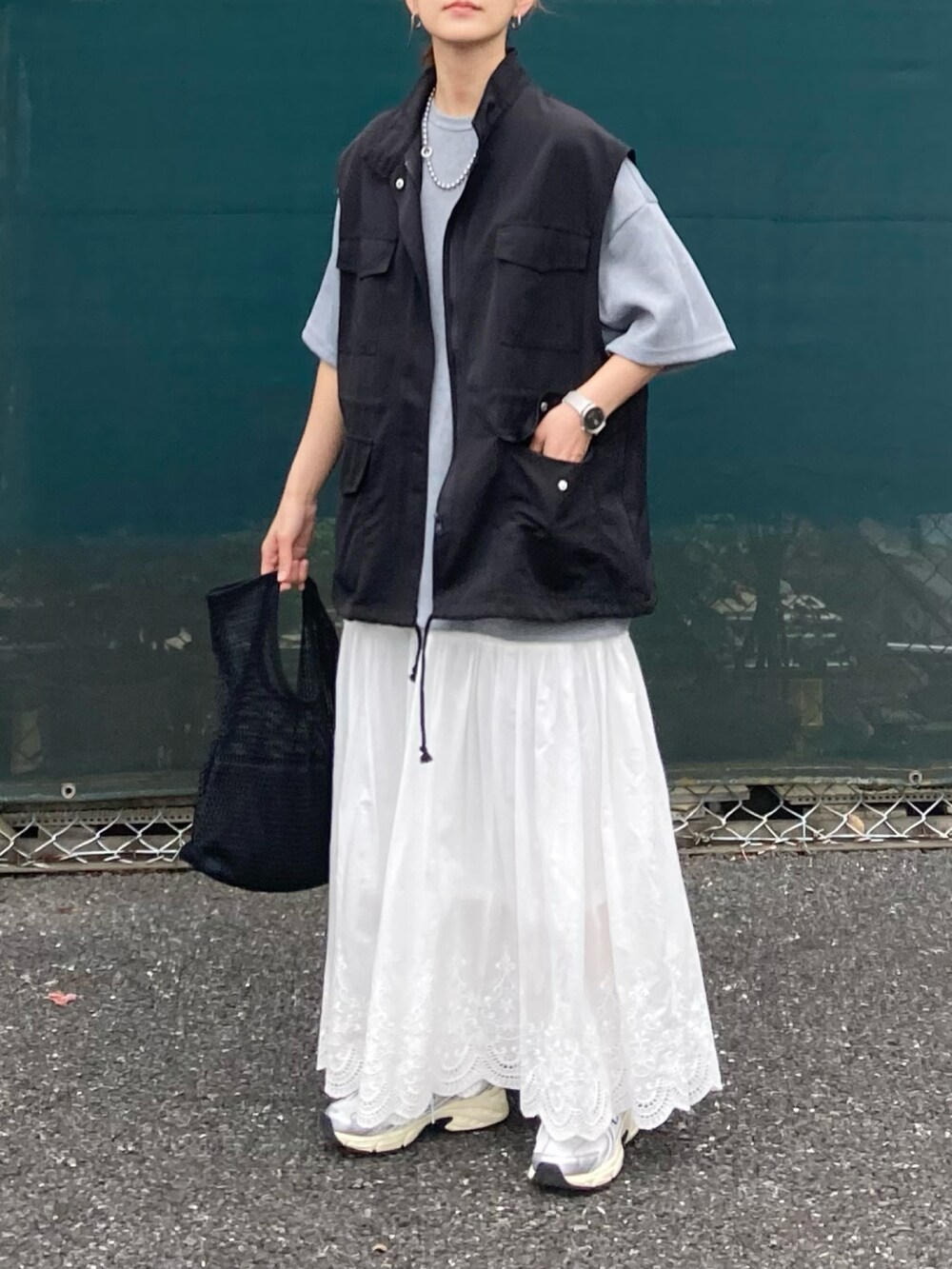 ブラック系のベスト、グレー系のTシャツ/カットソー、ホワイト系のスカートを着用したレディースの夏コーディネートの2枚目の写真