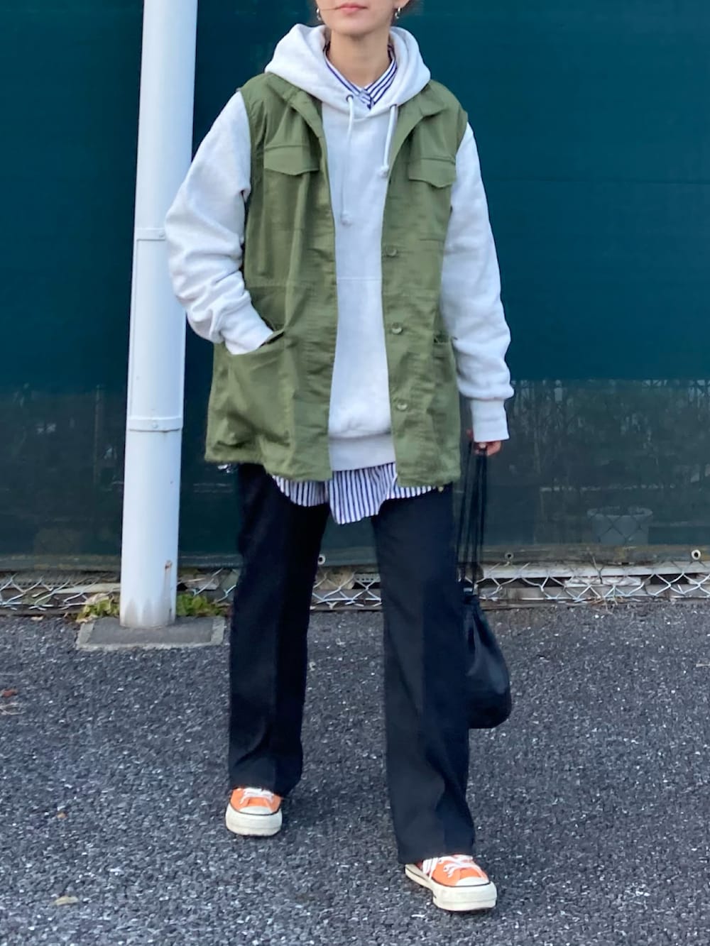 グリーン系のベスト、グレー系のパーカー、ブラック系のスラックスを着用したレディースの冬コーディネートの3枚目の写真