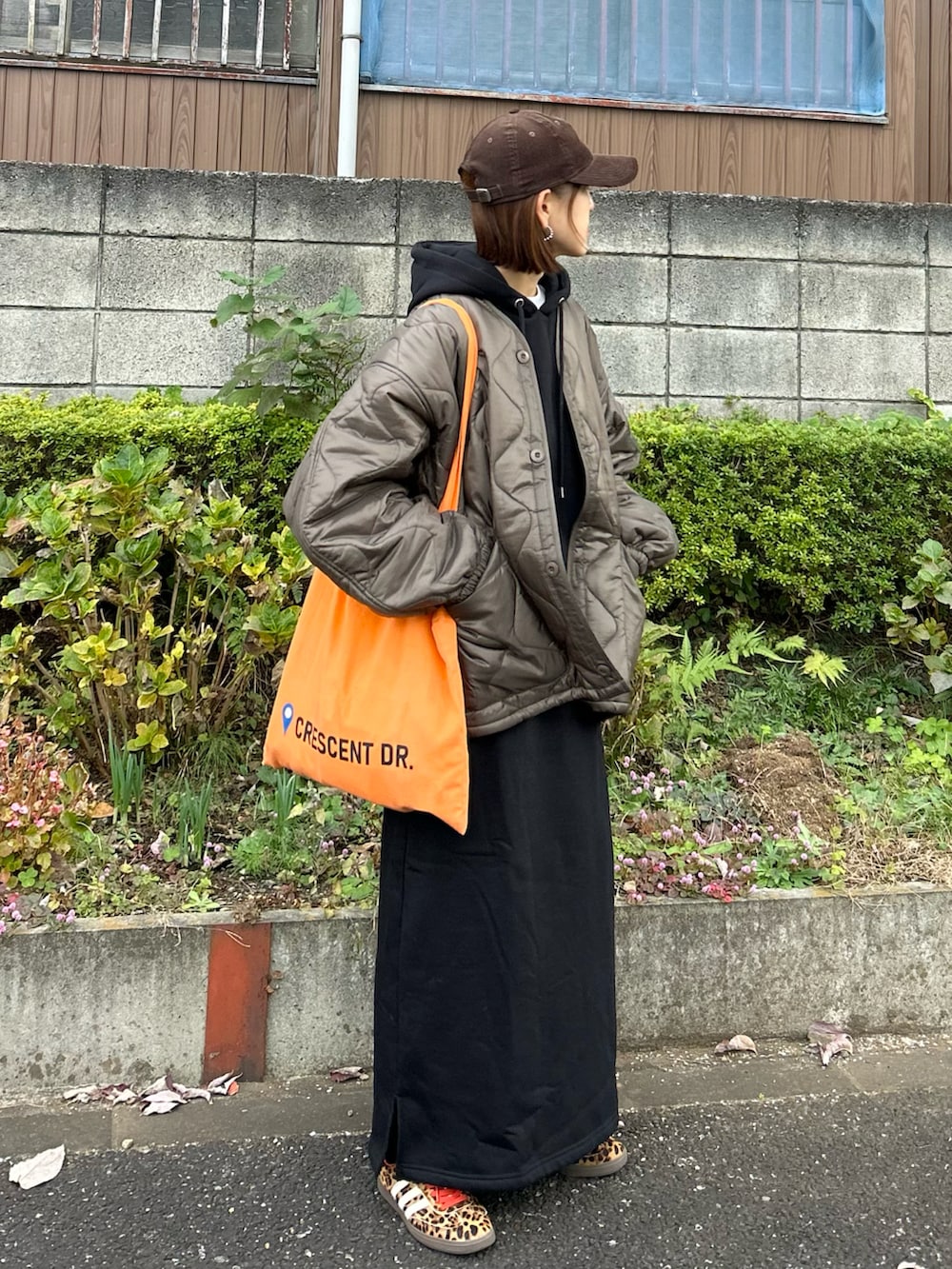 ブラウン系のブルゾン、ブラック系のワンピース、オレンジ系のトートバッグを着用したレディースの冬コーディネートの2枚目の写真