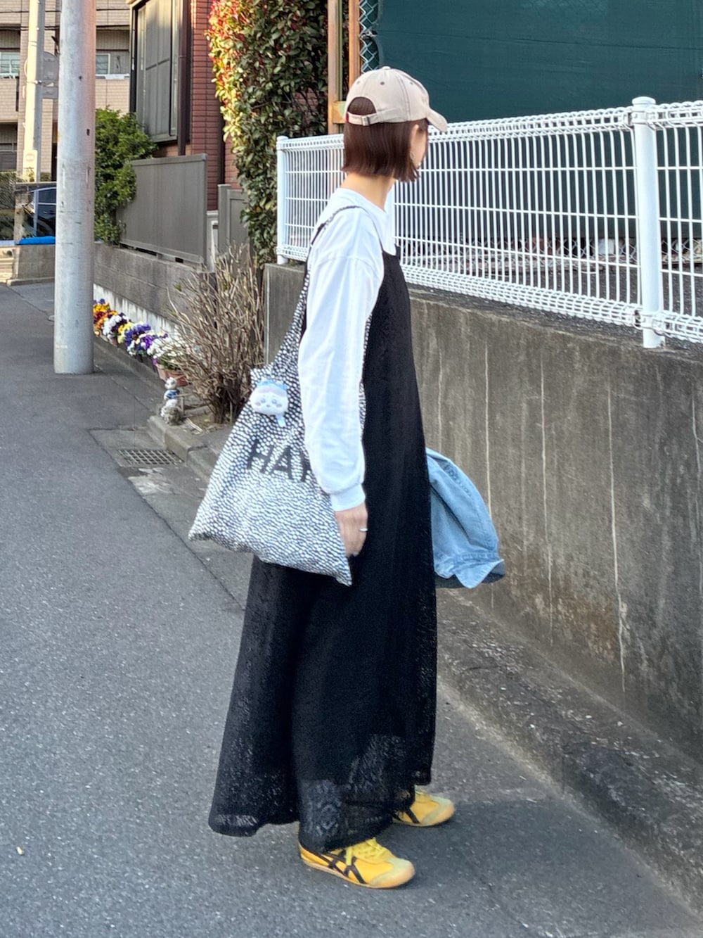 ブルー系のデニムジャケット、ブラック系のワンピース、イエロー系のスニーカーを着用したレディースの春コーディネートの5枚目の写真