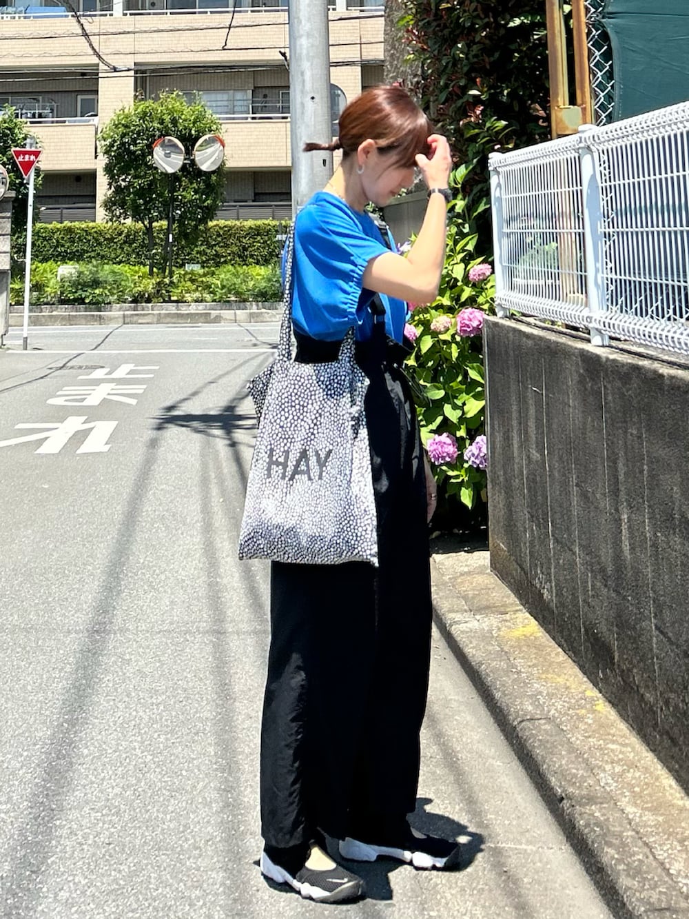 ブルー系のTシャツ/カットソー、ブラック系のジャンパースカート、ブラック系のスニーカーを着用したレディースの夏コーディネートの3枚目の写真