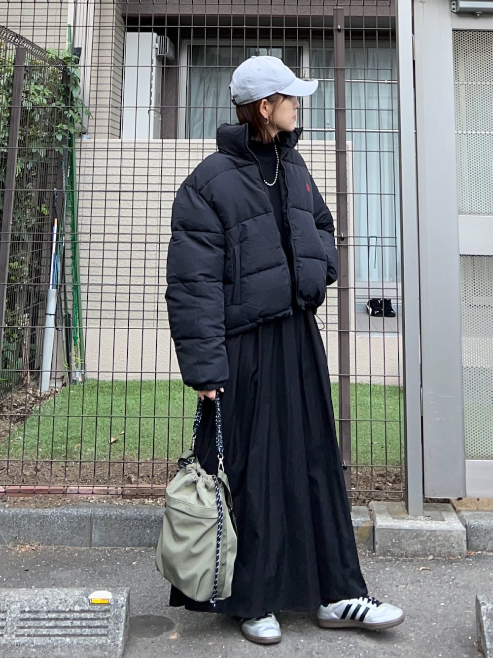 ブラック系のダウンジャケット/コート、ブラック系のワンピース、グリーン系のトートバッグを着用したレディースの秋コーディネートの2枚目の写真