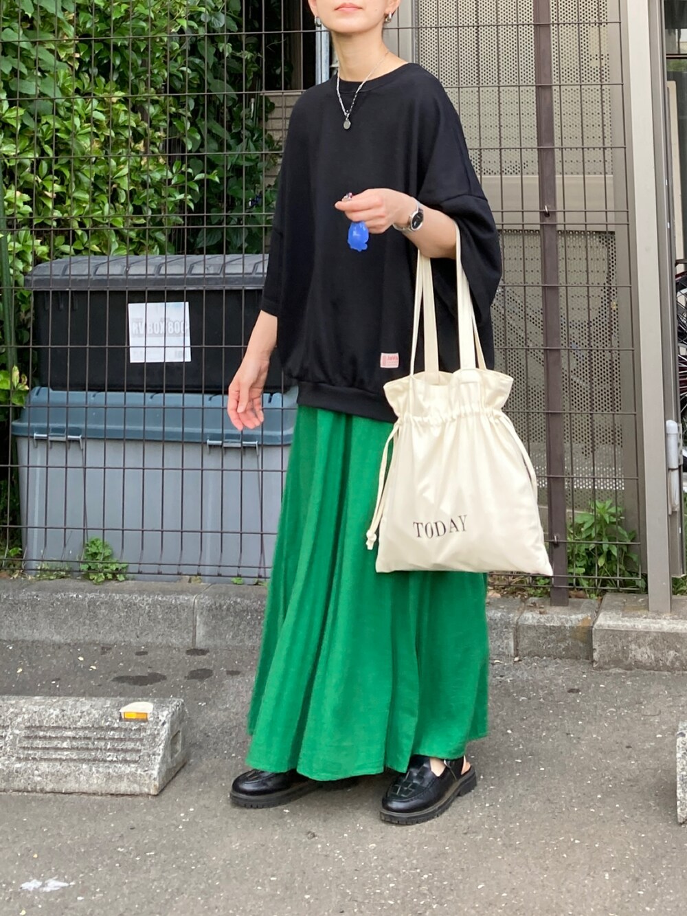 ブラック系のスウェット、ホワイト系のトートバッグ、グリーン系のスカートを着用したレディースの秋コーディネートの3枚目の写真