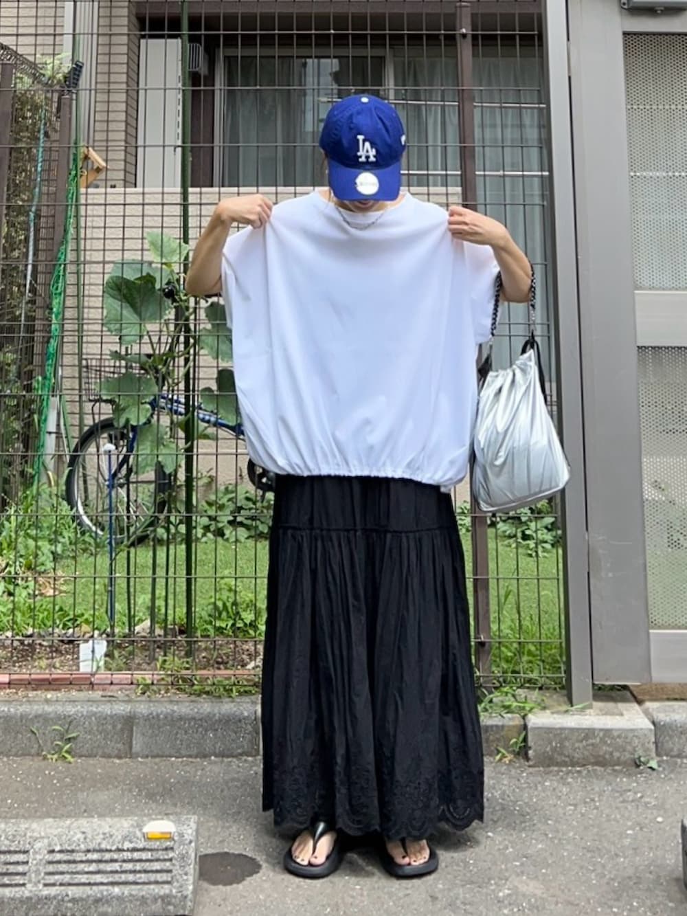 ホワイト系のTシャツ/カットソー、シルバー系のトートバッグ、ブラック系のスカートを着用したレディースの夏コーディネートの3枚目の写真