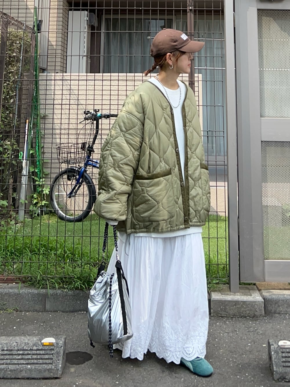 ホワイト系のスカート、シルバー系のトートバッグ、グリーン系のスニーカーを着用したレディースの秋コーディネートの2枚目の写真