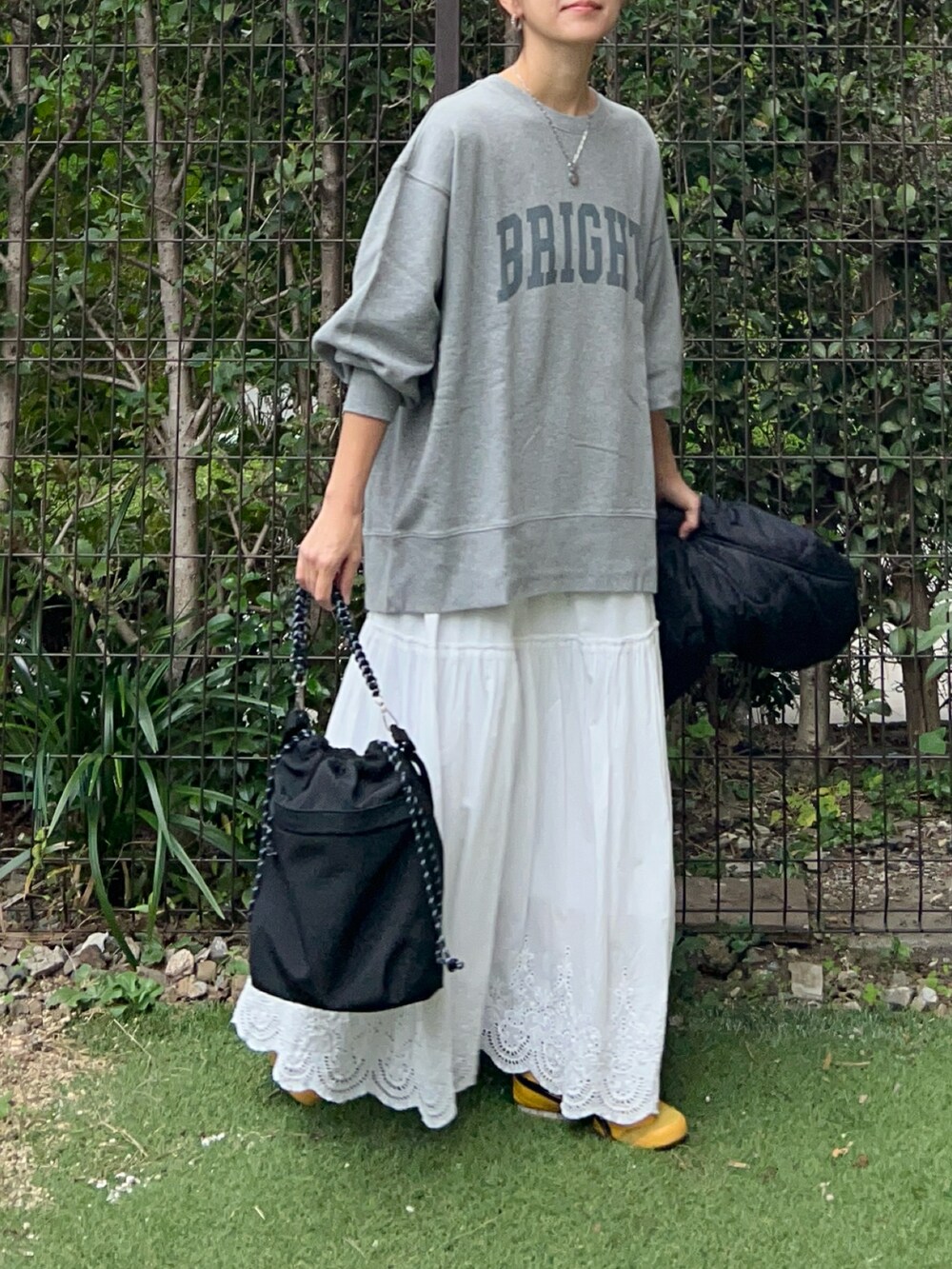 グレー系のスウェット、ホワイト系のスカート、ブラック系のトートバッグを着用したレディースの秋コーディネートの2枚目の写真