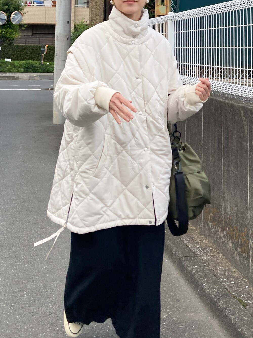 ホワイト系のブルゾン、ブラック系のワンピース、グリーン系のショルダーバッグを着用したレディースの秋コーディネートの3枚目の写真