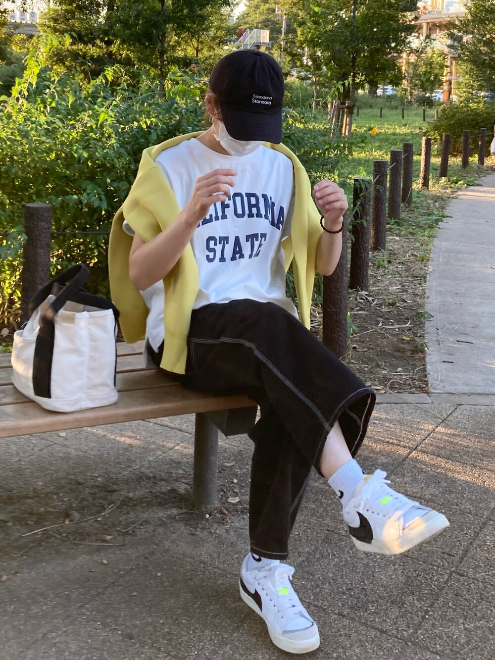 ホワイト系のTシャツ/カットソー、イエロー系のカーディガン/ボレロ、ブラック系のデニムパンツを着用したレディースの秋コーディネートの2枚目の写真