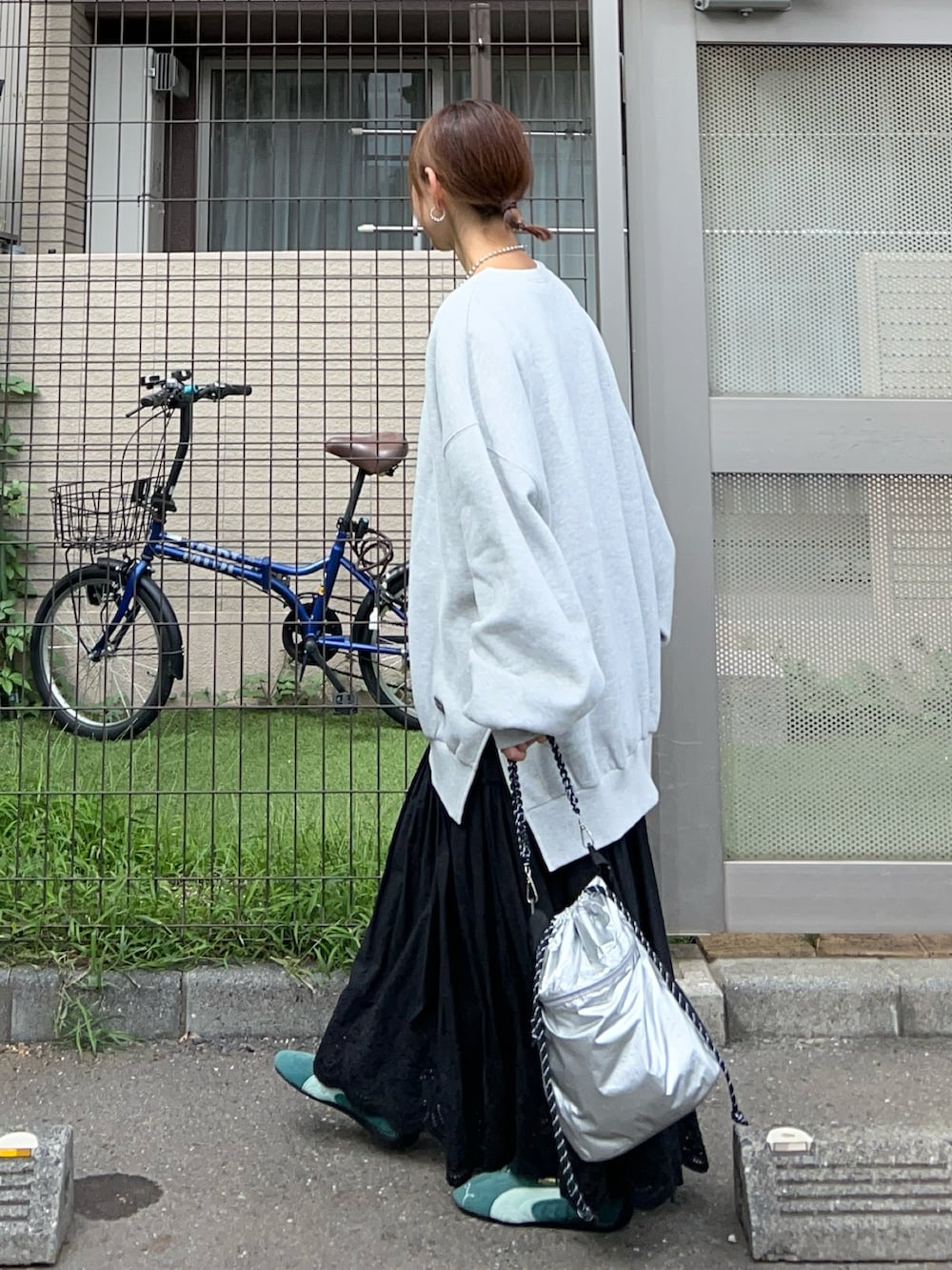 グレー系のスウェット、シルバー系のトートバッグ、ブラック系のスカートを着用したレディースの冬コーディネートの2枚目の写真