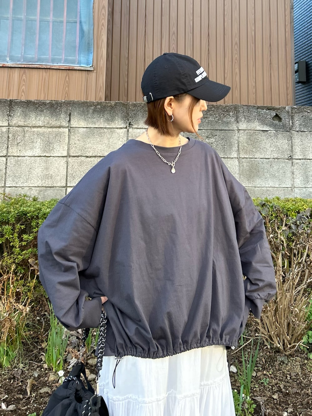 グレー系のTシャツ/カットソー、ブラック系のトートバッグ、ホワイト系のスカートを着用したレディースの冬コーディネートの4枚目の写真