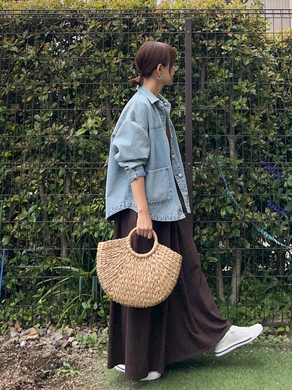 ブルー系のデニムジャケット、ブラウン系のワンピース、ベージュ系のかごバッグを着用したレディースの夏コーディネートの5枚目の写真