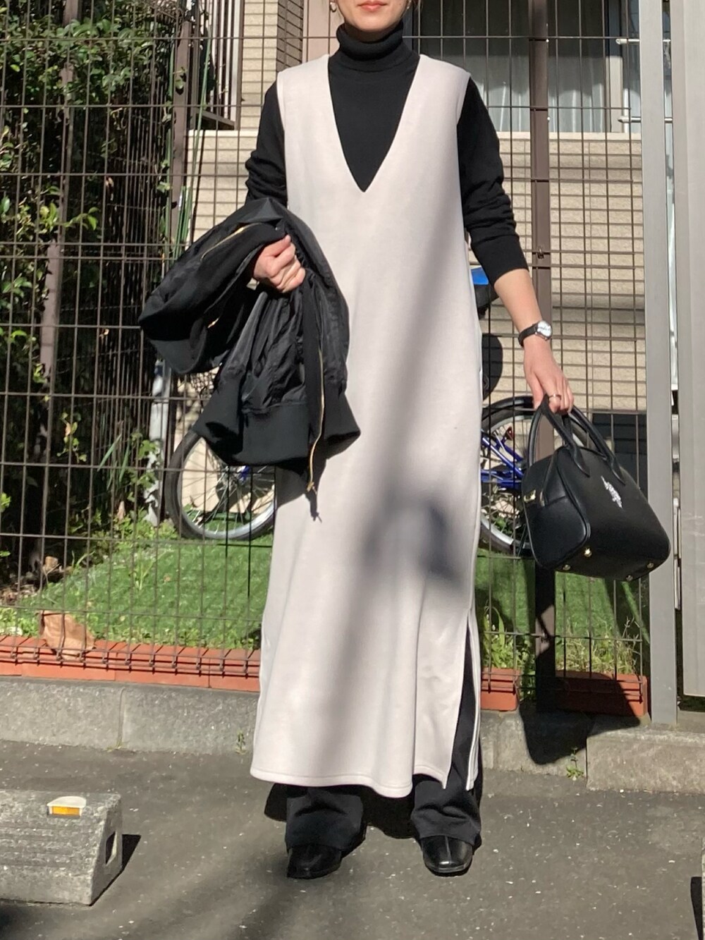 ベージュ系のジャンパースカート、ブラック系のハンドバッグ、ブラック系のアナログ腕時計を着用したレディースの冬コーディネートの2枚目の写真