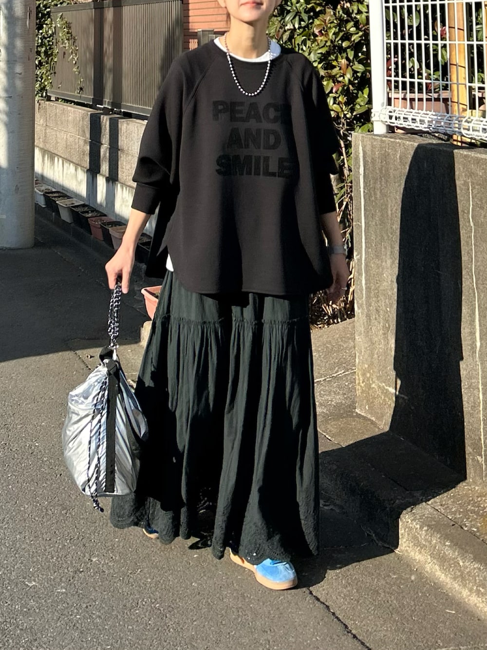 ブラック系のTシャツ/カットソー、ブラック系のスカート、シルバー系のショルダーバッグを着用したレディースの冬コーディネートの5枚目の写真