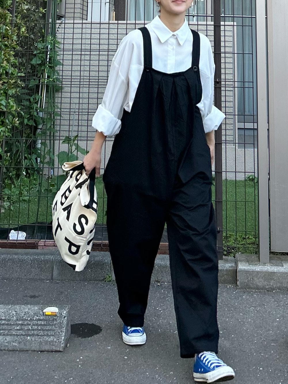 ホワイト系のシャツ/ブラウス、ブラック系のサロペット/オーバーオール、ブルー系のスニーカーを着用したレディースの春コーディネートの5枚目の写真